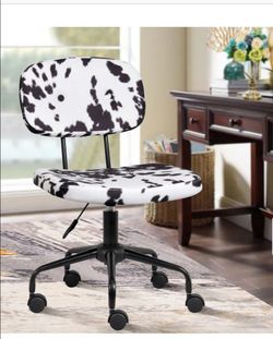 Adjustable armless swivel office chair in plush faux cowhide, black and white cow print.