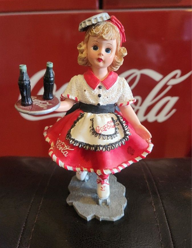 The Coca Cola Carhop "Doll Face" 1999 Madam Alexander-E 1/2856 is a collectible decorative item made of resin with a colorful Americana style design. 