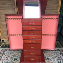 Burgundy Jewelry Armoire with Mirror , 8 drawers, Top compartment , and compartment doors on each side with several hooks inside. Pink Velvet linings.