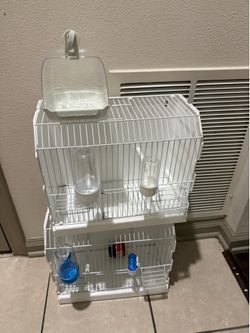 Two birdcages, including a clear bird bath.