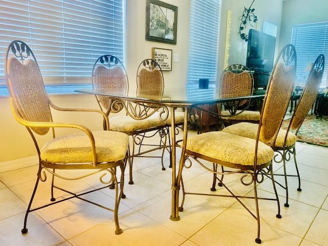 Dining Set Including sturdy Iron Table with 6 chairs. The top is rectangular glass, the base is sturdy iron scroll with rattan accents