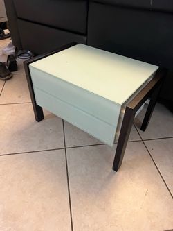 modern 2-drawer bedside nightstand featuring dark wood-finished frame legs and a light mint-green or frosted glass top and drawer fronts.