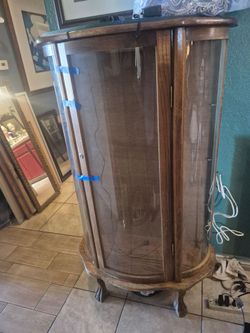 vintage oak curio cabinet with a curved glass front and claw feet.