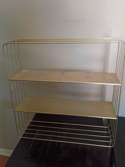 Gold shelf that hangs on the wall
