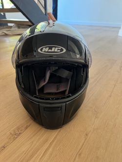 glossy black HJC modular motorcycle helmet featuring the brand's signature oval logo centered above the clear face shield.