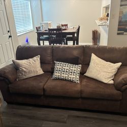 Brown leather couch with pillows in good condition