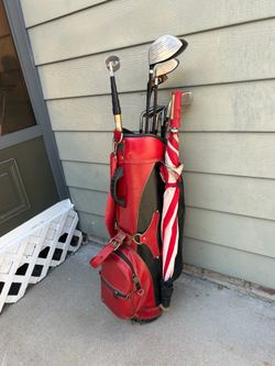 Touring vintage golf clubs with red bag, umbrella, and lots of golf balls Touring vintage golf clubs with red bag, umbrella, and lots of golf balls