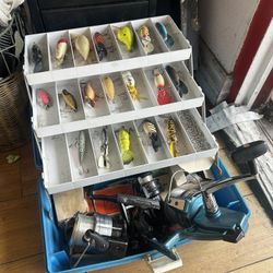 Vintage fishing tackle box filled with various fishing lures, hooks, and reels