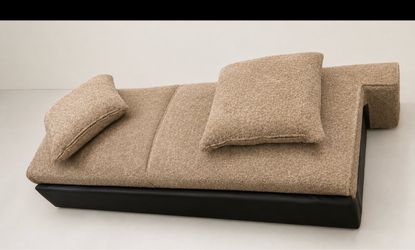 Beautiful modern beige bouclé chaise lounge with a sleek, low-profile design. Soft textured fabric, comfortable padded surface, and two matching pillo