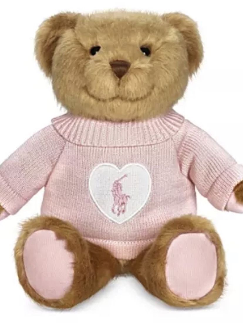 THE NEW 2021 LIMITED EDITION ROMANCE POLO BEAR BY RALPH LAUREN. THE BEAR IS BROWN WITH A PINK SWEATER. THE SWEATER HAS BOTH A WHITE HEART AND THE POL