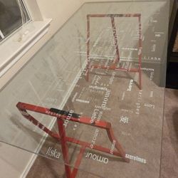 Glass top desk with red legs. Love written in Various language
