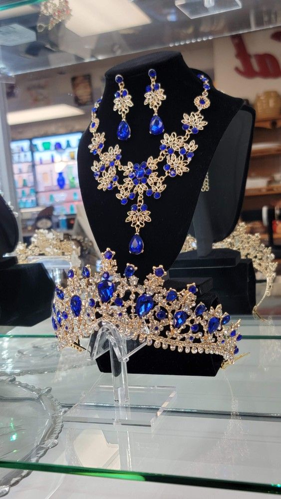 Gold-toned regal tiara with upsidedown blue teardrop gemstones and rhinestone accents, matching necklace/earrings