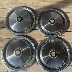 four vintage Cadillac hubcaps