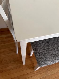 White dining table with 3 chairs and a bench in blue.