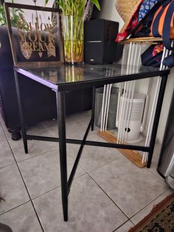 2 black metal end table with a glass top and a cross-leg design