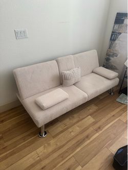 Beige futon bed with cup holders and pillows