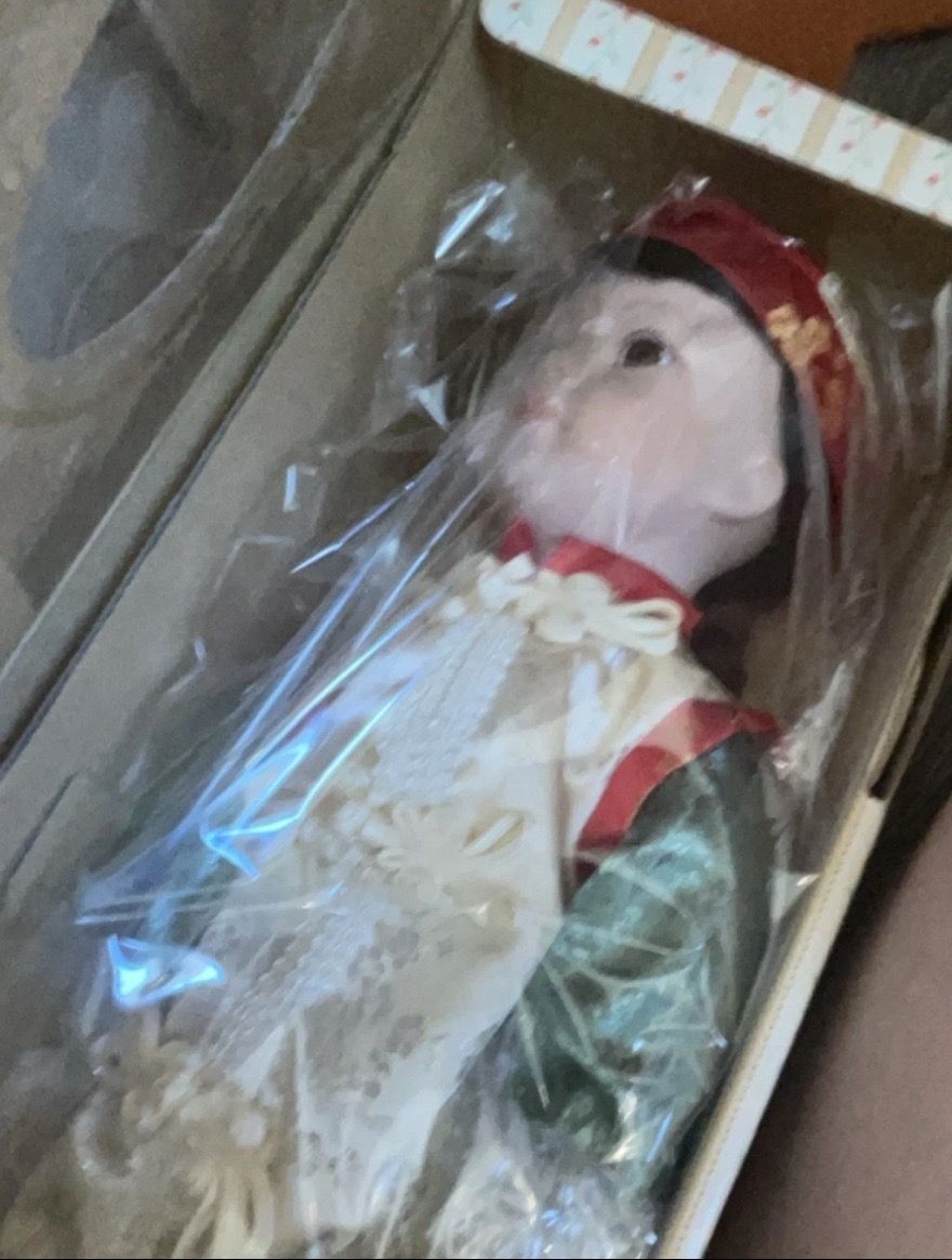 This is a vintage porcelain doll featuring traditional-style clothing