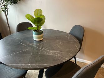 Black marble effect table with four gray dining chairs
