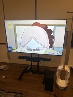 Large Flat Screen TV on Mobile Floor Stand by and sound bar