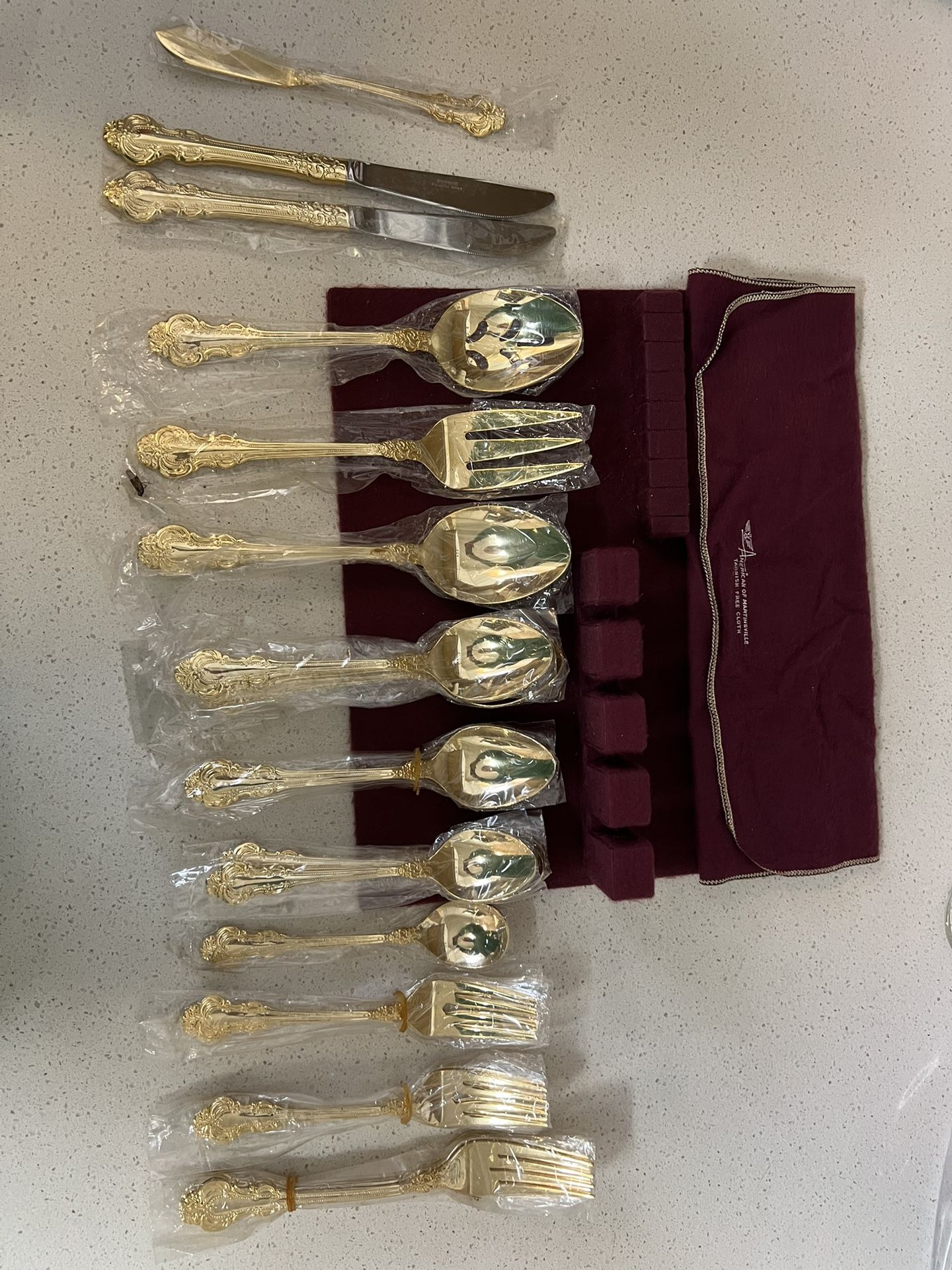 of gold-plated flatware in a burgundy storage case. This type of cutlery is typically electroplated with 23K gold over a stainless steel base. The se