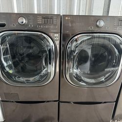 stainless steel Gray front-load set washer and dryer with high-capacity with pedestals.