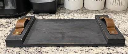 Solid wooden serving tray or decorative riser resting on a kitchen countertop must pick up