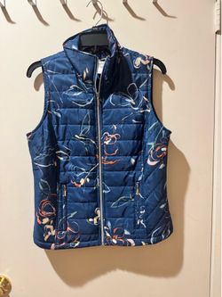 Lightweight vest with a navy floral print. Stand collar and full zip for easy layering. Two zip pockets keep essentials secure. Soft insulation for wa