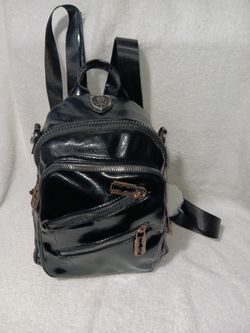 This is a small black patent faux leather backpack with multiple zipper pockets.