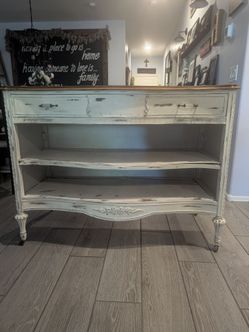 Refurbished Distressed white wood sideboard has a natural wood top and a top drawer
 with decorative glass and metal pulls. This piece features an ope