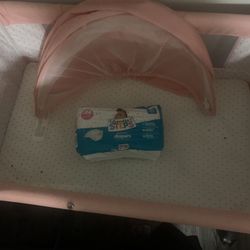 Pink Bassinet And Newborn Diapers