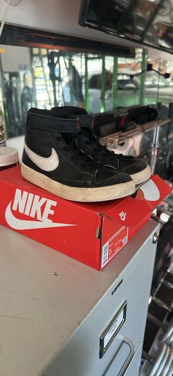 Pre-owned Nike Blazer Mid '77 sneakers in size 2Y. These high-top shoes are black leather with white swoosh logos and suede accents on the toe. The so