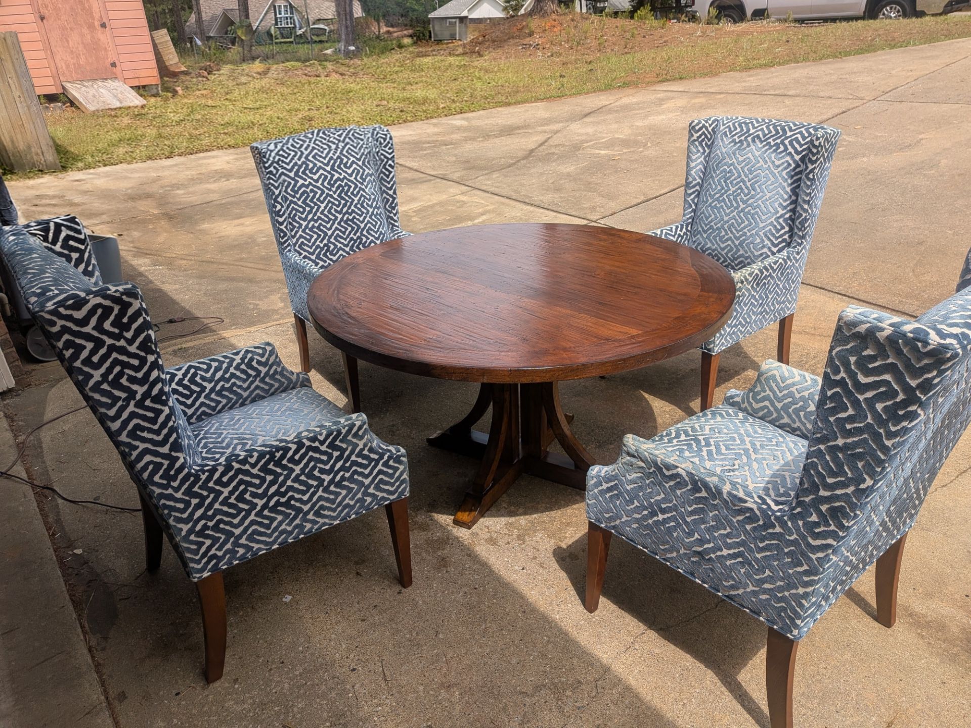 Round Wood Pedestal Dining Table with 4 Upholstered Wingback-Style Chairs.