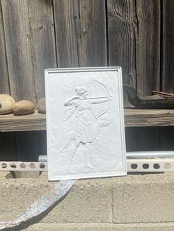 white relief sculpture of a female archer