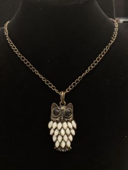 $10. Brass colored owl pendant with white plastic colored feathers and black eyes. Necklace is 30 in. Our pendant is 2 in long and 1 in wide.