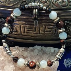 A combination of red. African tiger eye. Moonstone and silver Color fob accents. Size medium