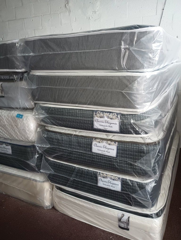 Have All Size Available Good Prices Todos Los tamaños Disponibles Stack of new mattresses wrapped in protective plastic. Multiple styles available.