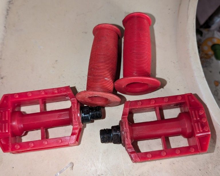 2 Tricycle Handle Bar Grips and 2 Pedals With Reflectors On Them.