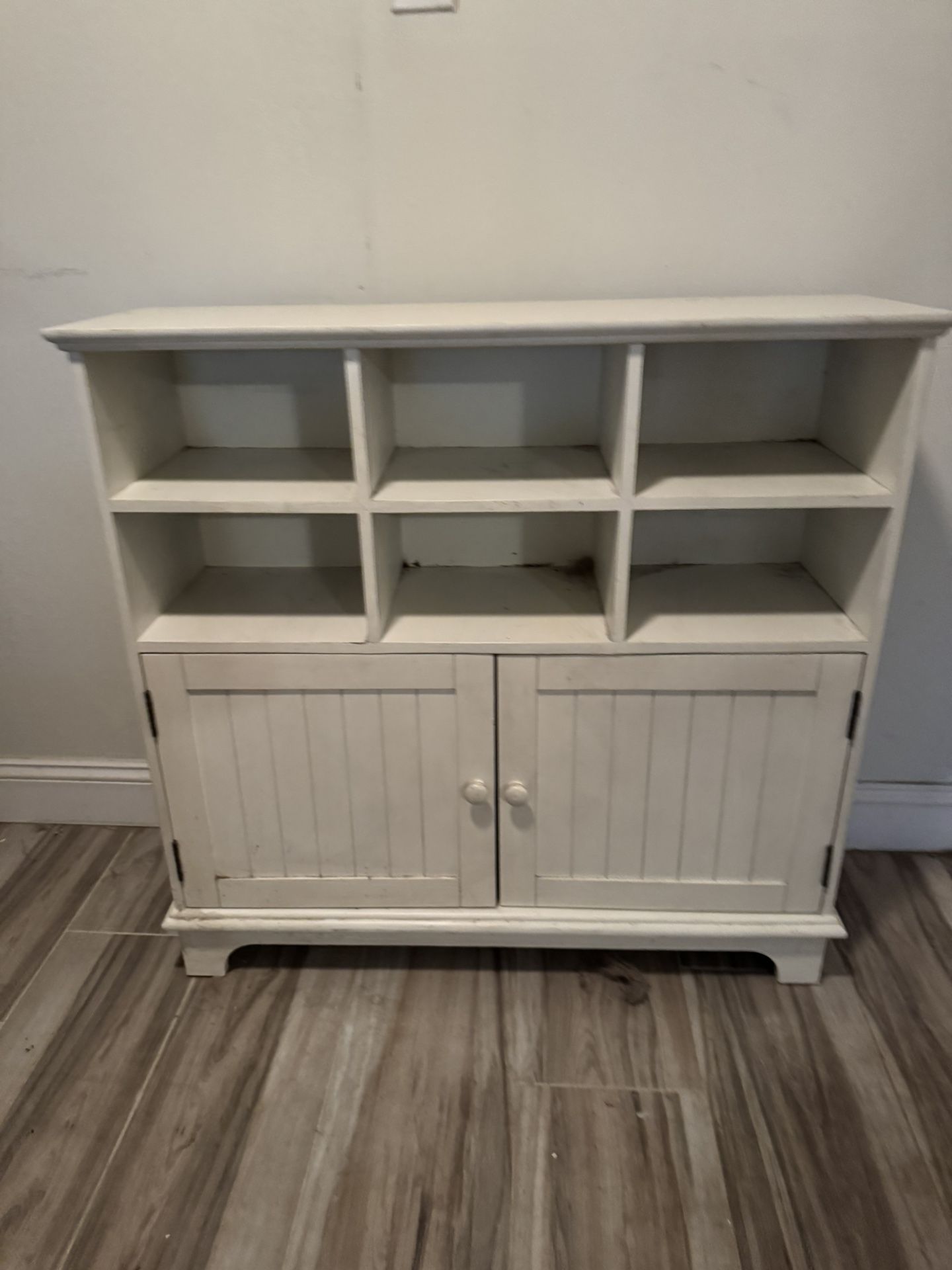This is a white wooden storage cabinet with six open shelves and two lower doors