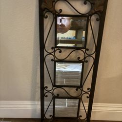 wrought iron wall mirror with a scroll design and three square mirror panels.     
