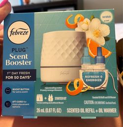 Febreze PLUG Scent Booster Starter Kit, featuring a white warmer device and a "Refresh & Energize" scented oil refill.