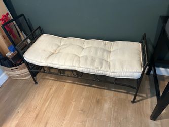 Wrought iron bench with padded cushion.