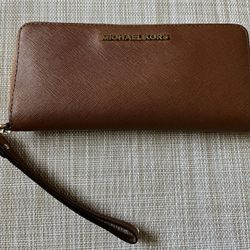 It’s A Michael Kors wristlet wallet the color is brown it is barely used