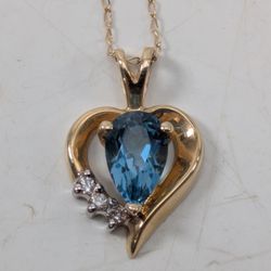 14K Yellow Gold Heart Necklace – Elegant 14K yellow gold heart pendant featuring one vibrant blue stone and three sparkling clear stone accents. Marke