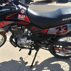 This item is a Honda XR150L, a lightweight dual-sport motorcycle designed for both street and off-road riding. • Engine: 149cc air-cooled, single-cyli