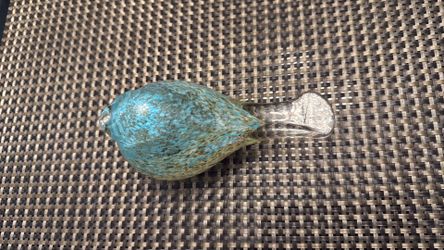 A handmade blown glass bird figurine with speckled blue and brown coloration,  paperweight.