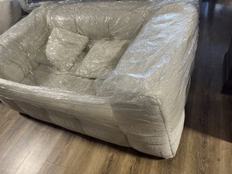 New beige fluffy sofa wrapped in plastic.