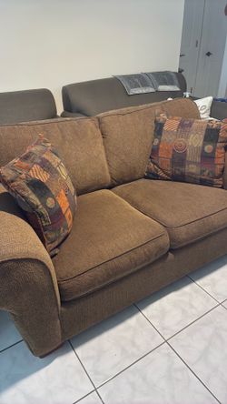 Brown Loveseat with 2 dec pillows.