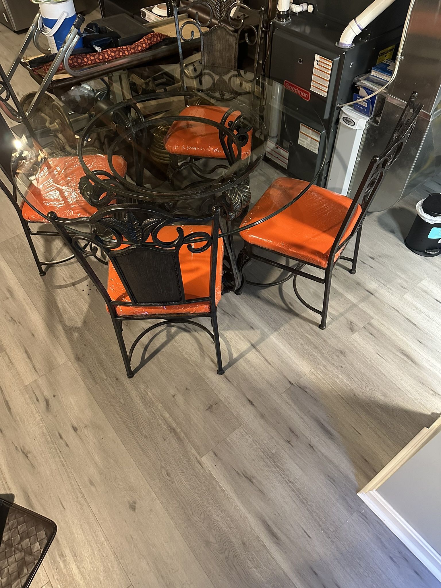 Beautiful Wrought Iron  & round glass dining table with 4 orange newly upholstered seats.
