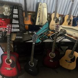 Diverse assortment of musical instruments includes multiple acoustic guitars from brands like Johnson and Jasmine, several violins in cases, clarinets