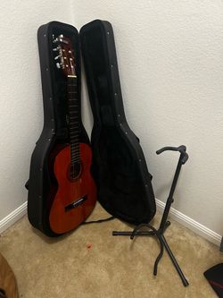Classical guitar with case, capo, and stand.